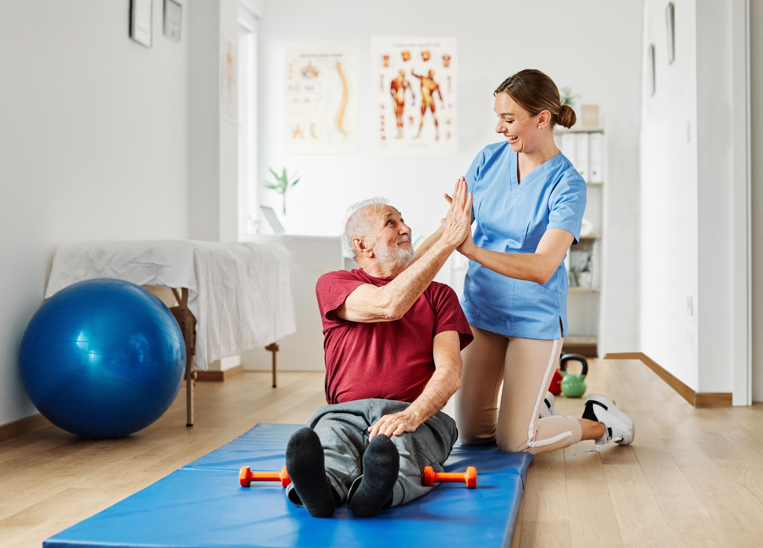 Physical Therapist Assistant high fiving an elderly patient